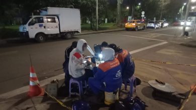 Un grupo de jóvenes técnicos de la ETB trabaja bajo la tenue luz de las farolas en una calle de Bogotá. Vestidos con chalecos reflectivos y cascos de seguridad, manipulan cables de fibra óptica, asegurando conexiones críticas mientras la ciudad duerme.